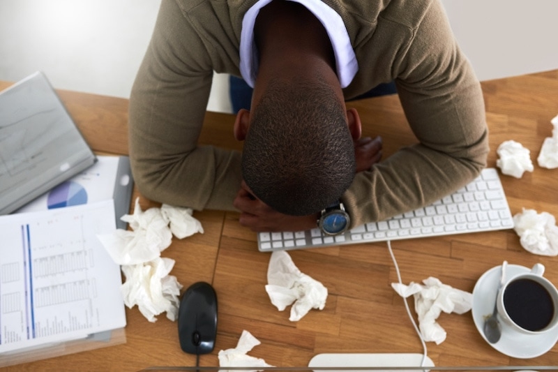 AC & Allergies - High angle shot of a young businessman feeling ill at his work desk