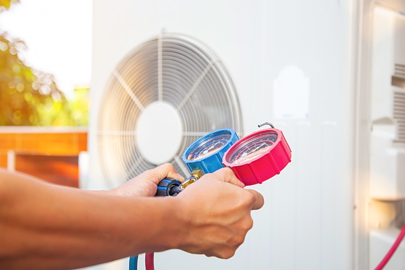 Hands of Technician are using a measuring tool to check heat pump evacuates air for air conditioner.